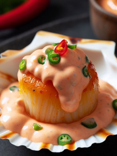 Una foto de Vieira rellena con mayonesa de coral y sriracha