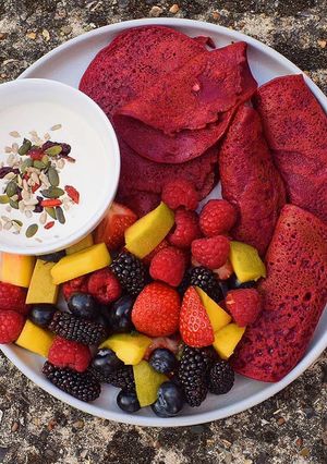 A picture of Beetroot pancakes with berries, mango with vegan yoghurt+seeds.