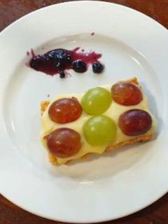 Una foto de Hojaldre con crema pastelera, diferentes tipos de uva y mermelada de frambuesa
