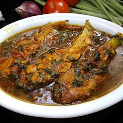 A picture of Fish curry with tomato and herbs.