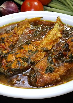 A picture of Fish curry with tomato and herbs.