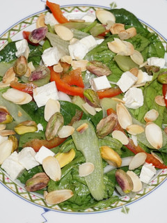 Una foto de ENSALADA DE ESPINACA BABY, ICEBERG CON QUESO DE CABRA, PISTACHO Y ALMENDRAS