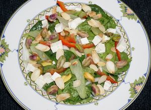 Una foto de ENSALADA DE ESPINACA BABY, ICEBERG CON QUESO DE CABRA, PISTACHO Y ALMENDRAS