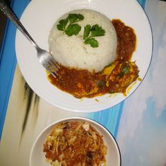A picture of Egg curry served with white rice and sauted cabbage.