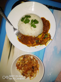 A picture of Egg curry served with white rice and sauted cabbage.