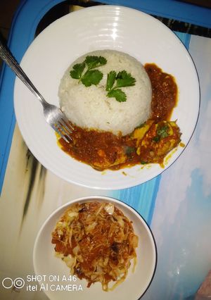 A picture of Egg curry served with white rice and sauted cabbage.