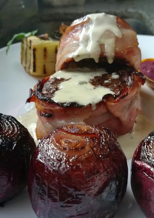 Una foto de Lomo envuelto en panceta con cajita de papa rellena y cebollas