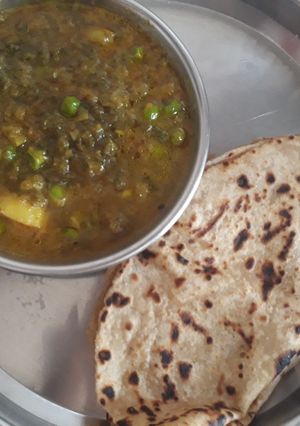 A picture of Green onion leaves, peas and potato curry.