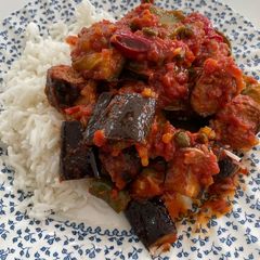 A picture of Sausages with roasted vegetables in a tomato sauce.