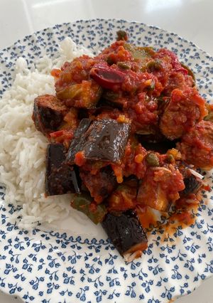 A picture of Sausages with roasted vegetables in a tomato sauce.