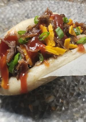 Una foto de Roast beef desmechado con panceta y cebolla caramelizada, en pan bao (pancitos al vapor)