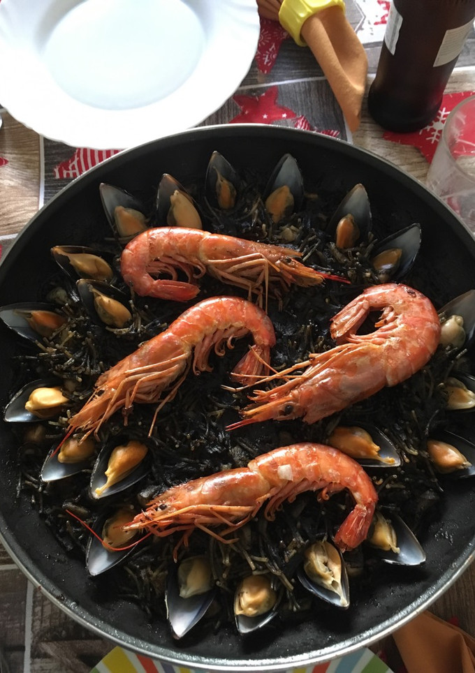 Una foto de Fideuà negra de sepia y gambas