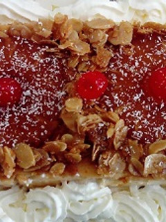 Una foto de Flan de queso con piña, almendras laminadas caramelizadas y nata