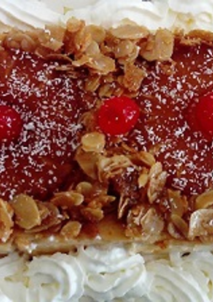 Una foto de Flan de queso con piña, almendras laminadas caramelizadas y nata