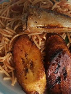 A picture of Jollof Spaghetti with fried plantain and fish.