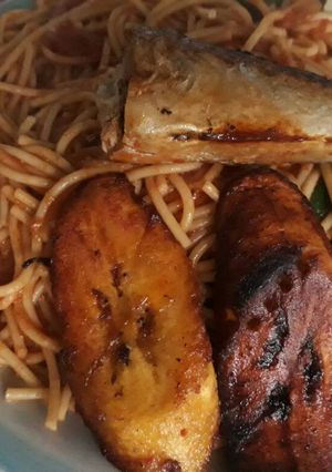 A picture of Jollof Spaghetti with fried plantain and fish.