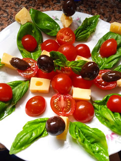 Una foto de Ensalada de albahaca, queso, tomates cherry y aceitunas negras