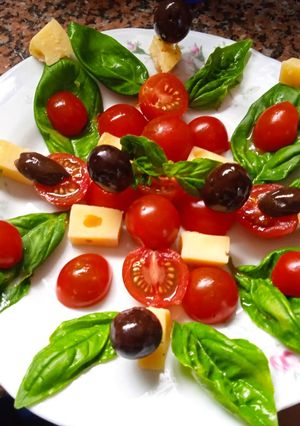 Una foto de Ensalada de albahaca, queso, tomates cherry y aceitunas negras
