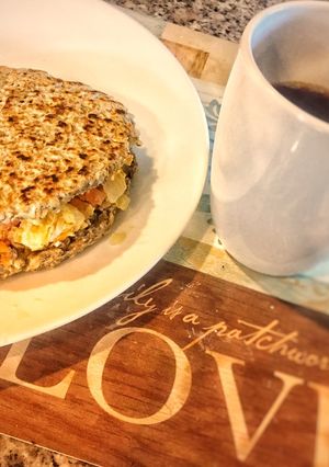 Una foto de Arepa fit de avena con semillas de chía.. rellena de huevos revueltos con vegetales 🍅 y café ☕️