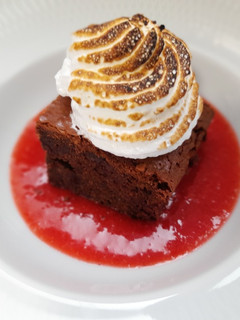 Una foto de Brownie de avellanas con salsa de fresas y merengue