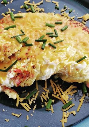 A picture of Sunday breakfast omelet with ham and cheese and chives.