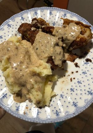 Una foto de Pollo frito con puré de papas y salsa cremosa