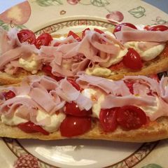 A picture of Panino aperto con caprino, pomodorini e cotto.