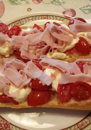 A picture of Panino aperto con caprino, pomodorini e cotto.