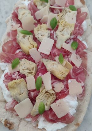 Une photo de Pinsa romana coppa, burrata, artichaut
