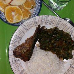 A picture of White rice with spinach and fried fish.