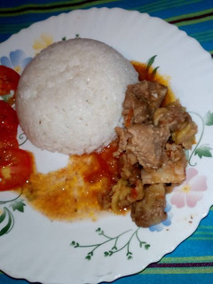A picture of Boiled rice /beef stew garnished with tomatoes.