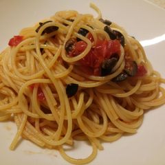 A picture of Spaghetti with fresh tomatoes, olives and basil.