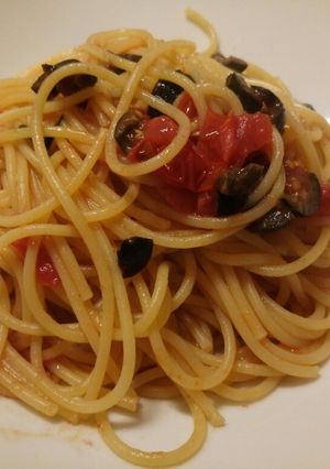 A picture of Spaghetti with fresh tomatoes, olives and basil.