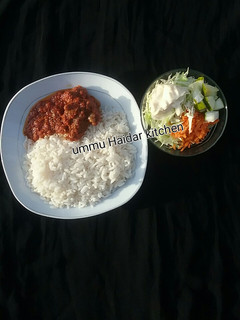 A picture of White rice with stew,meat and coslow.