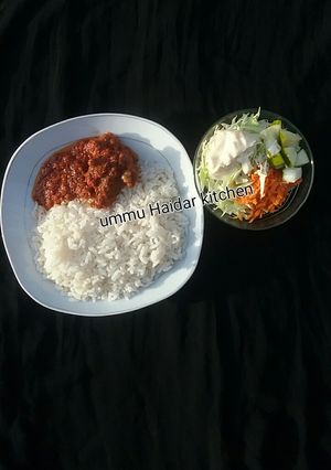 A picture of White rice with stew,meat and coslow.