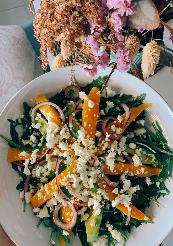 Una foto de Ensalada de rúcula con mango, aguacate, cebolla morada y feta