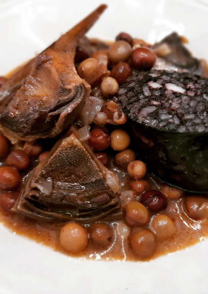 Una foto de Guisantes negros con alcachofas y morcilla de arroz