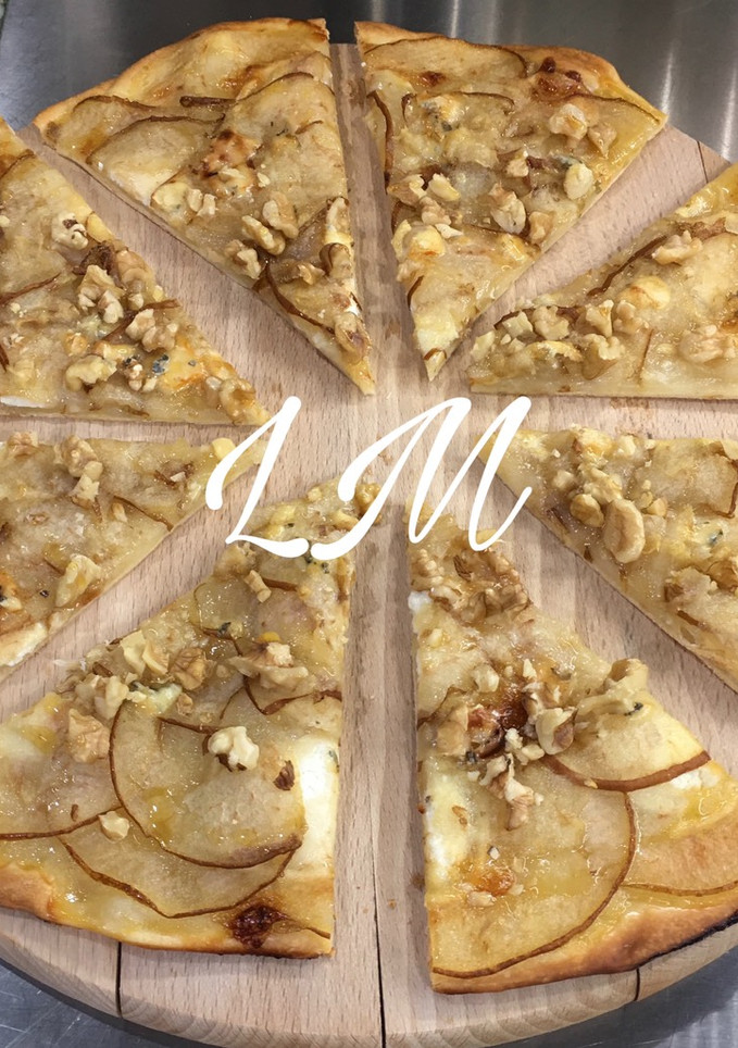 Una foto de Pizza de queso de cabra, pera, queso roquefort, nueces y miel