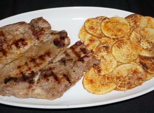 Una foto de Chuletas de cerdo vetadas asadas a la plancha y chips de papas a la parmesana