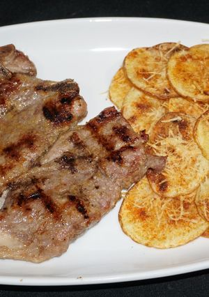 Una foto de Chuletas de cerdo vetadas asadas a la plancha y chips de papas a la parmesana