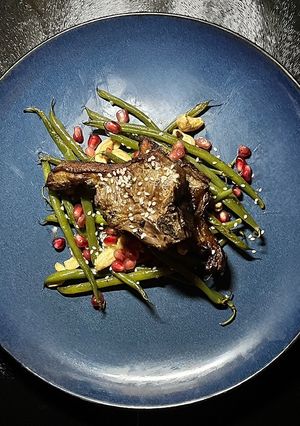 A picture of Asian lamb chops with fried beans and cashew nuts.