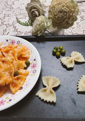 A picture of Creamy Red sauce Farfalle Pasta with green peas.
