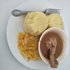 A picture of Mashed potatoes with stewed chicken and cabbage.