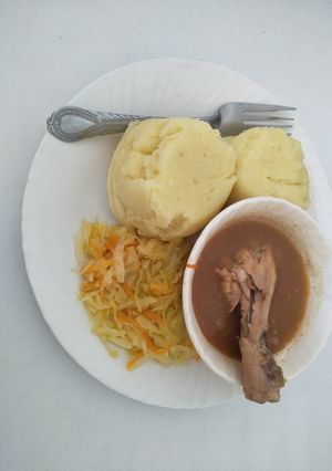 A picture of Mashed potatoes with stewed chicken and cabbage.
