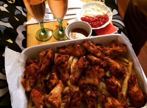 Una foto de Alitas de pollo con una cama de papas fritas