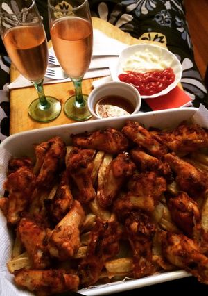 Una foto de Alitas de pollo con una cama de papas fritas