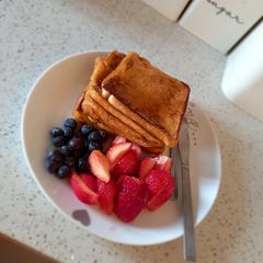 A picture of French toast with berries and honey.