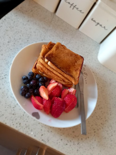 A picture of French toast with berries and honey.