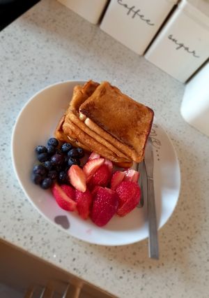 A picture of French toast with berries and honey.