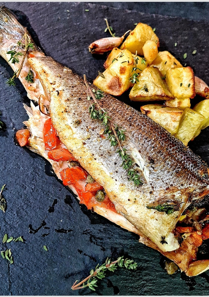 Una foto de Lubina rellena acompañada con patatas asadas al tomillo